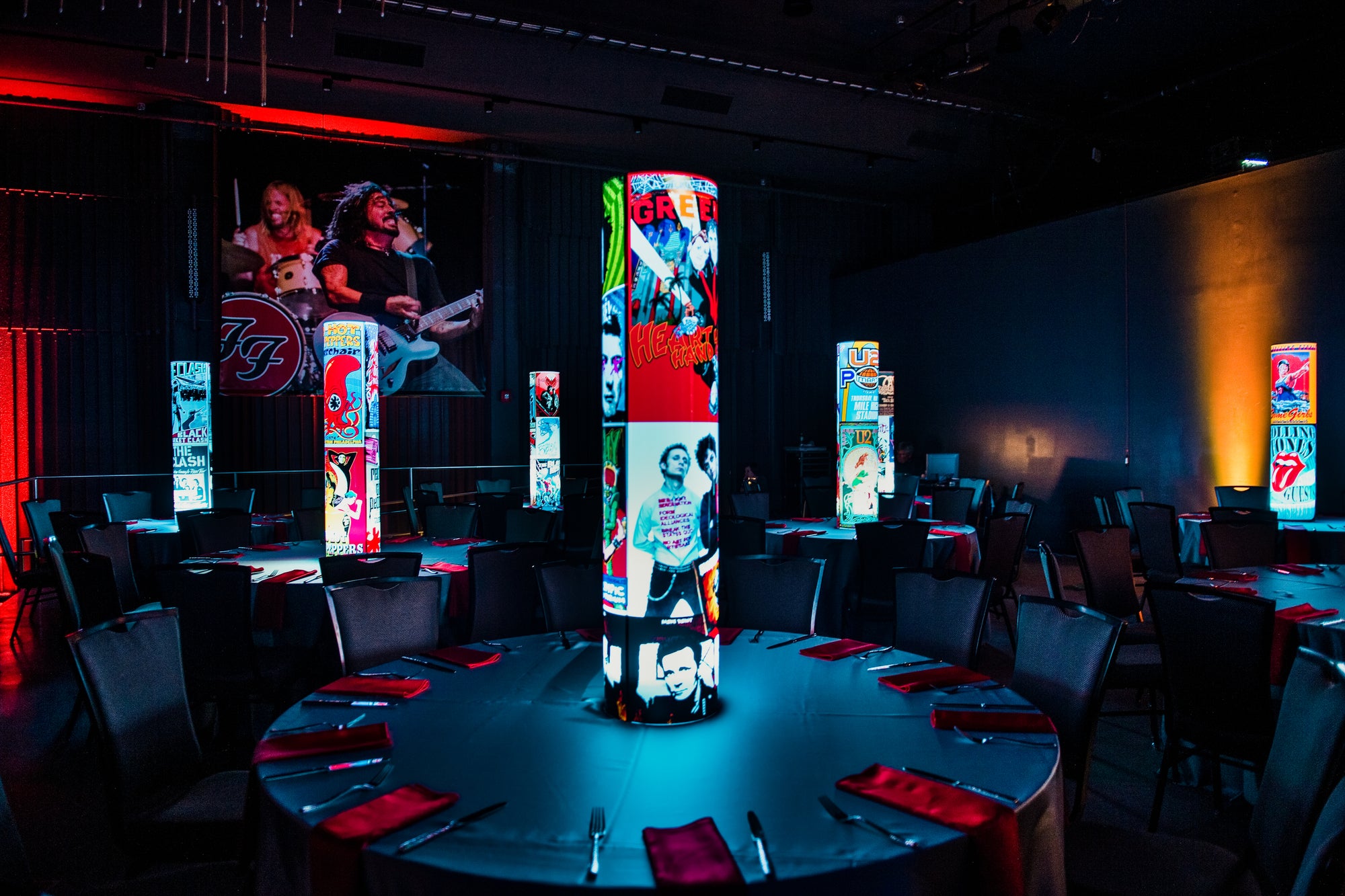 Dining area with colorful cylindrical light fixtures and people in the background