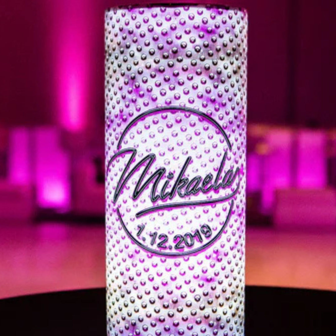 Decorative can with 'Mikaella' and a date on a blurred pink and purple background