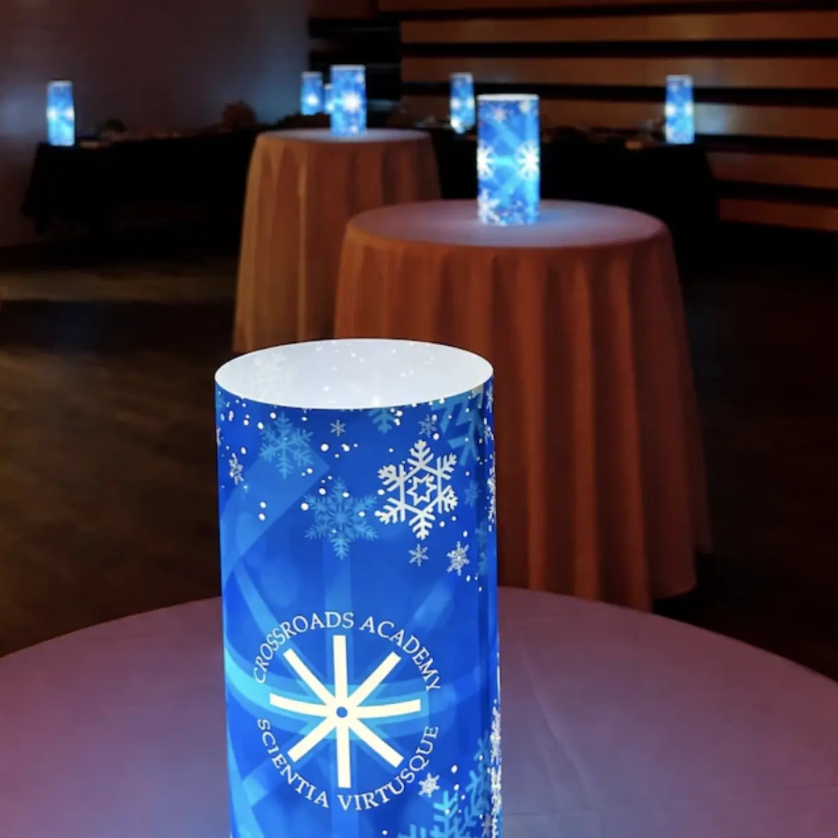 A blue illuminated centerpiece repeating an academy identity across a real event room