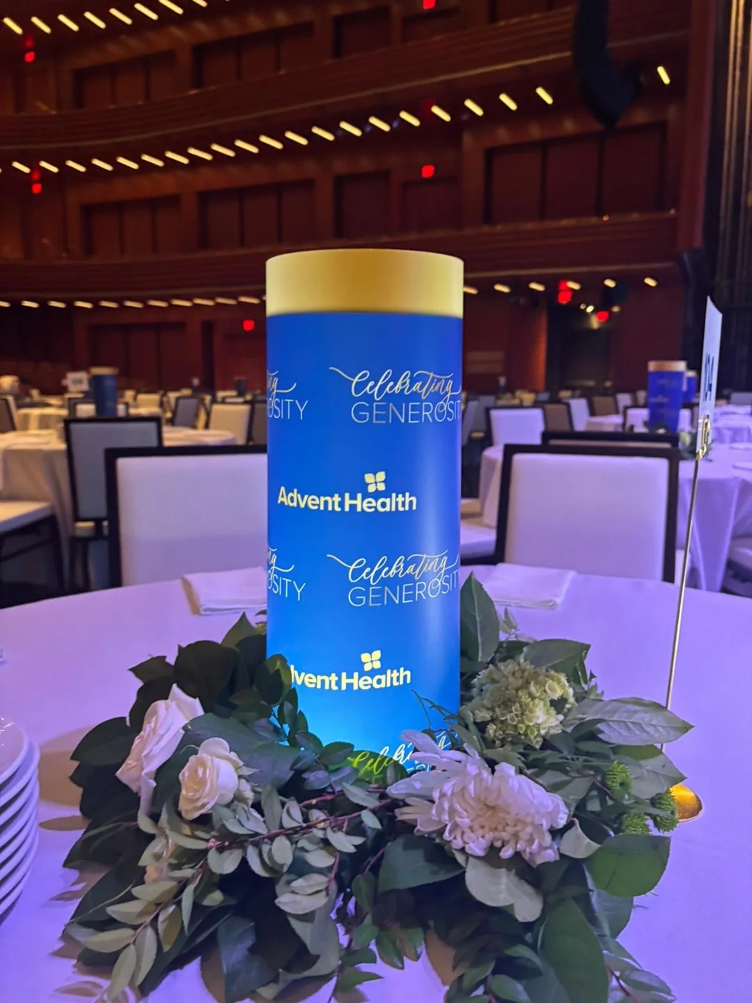 Blue branded illuminated centerpiece integrated with greenery