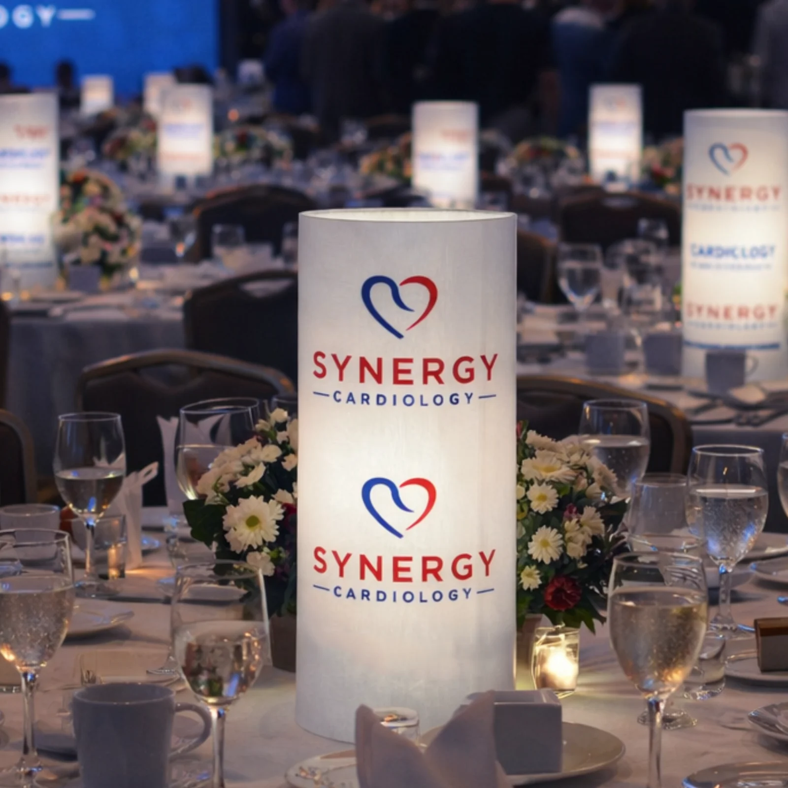 White branded illuminated centerpiece integrated with flowers at a formal event